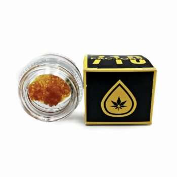 Close-up view of Factory 710 Mandarin Cookies - Full Spectrum concentrate in a glass jar, accompanied by branded packaging. Premium cannabis product.
