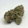 Grape Ape AAA indica cannabis flower bud, dense frosty nug with orange pistils, THC 17-23%
