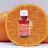 A bottle of Sky High Edibles THC Syrup – Orange 3000mg placed in front of a fresh, sliced orange on a plain white background.